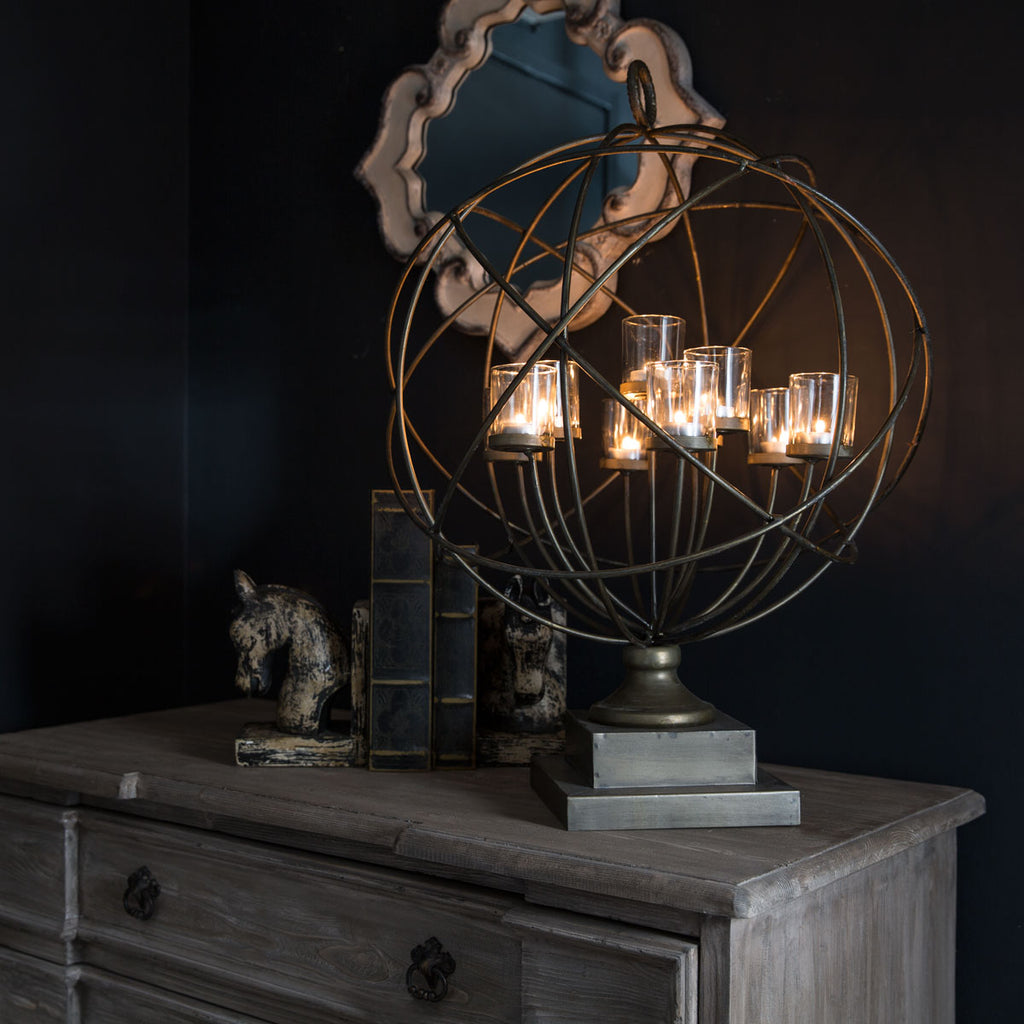 Side table with a metal globe candle holder and old books displayed on it