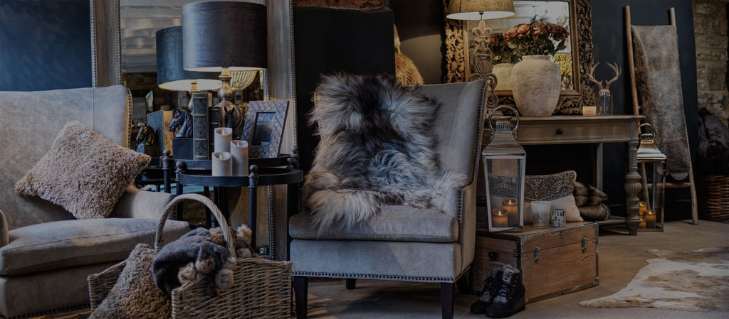 a studded armchair in beige with a sheepskin throw on it cotswold luxe home interiors