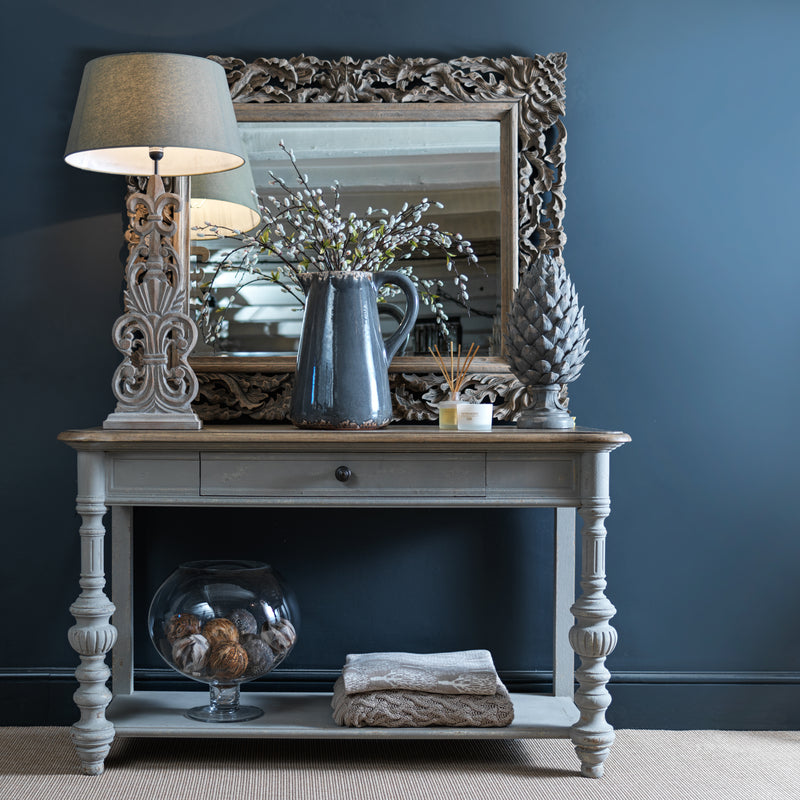a sideboard table holds a lamp, mirror and other decorative accessories at costwold luxe interiors